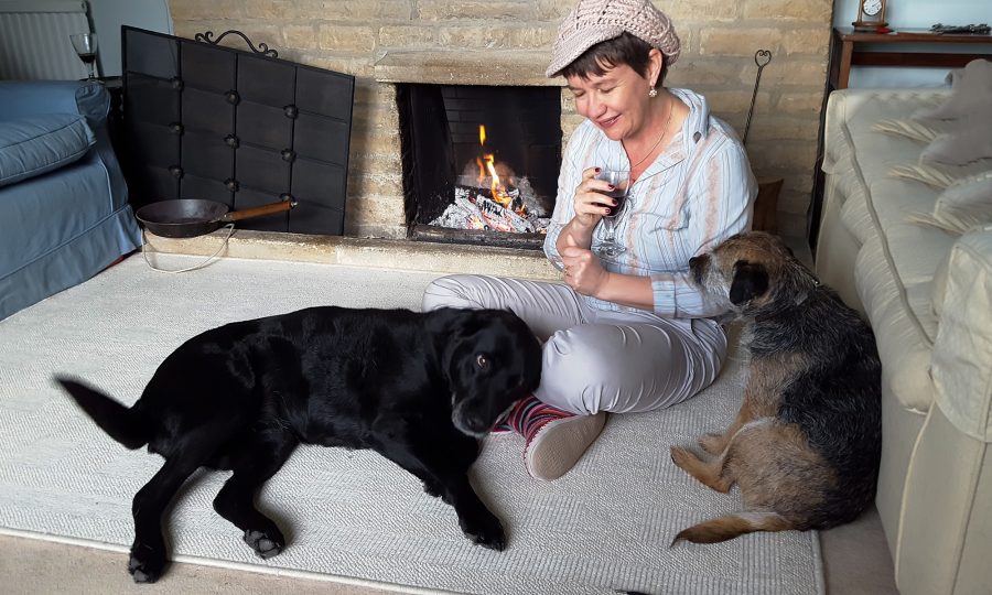 Woman sits by fire with two dogs